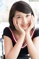 A young woman sitting at a table with her hands on her face.